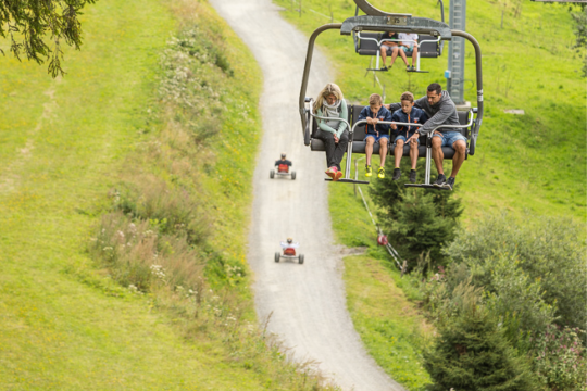 Familie fährt im Sommer mit Lift und darunter fahren die Gäste mit den Mountaincarts, © Martin Fülöp