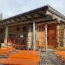 Wooden hut with terrace and benches outside.
