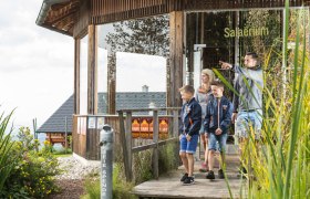 Familie auf Holzweg vor einem Geb&auml;ude mit der Aufschrift 'Salaerium'.