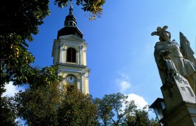 Turm der Pfarrkirche Gro&szlig;weikersdorf mit Statue im Vordergrund.