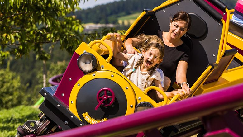 Eine Frau und ein Kind im Waggon einer Achterbahn im Eis-Greissler Erlebnispark.