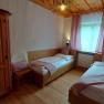 Cozy bedroom with two single beds, wooden furniture and pink curtains.