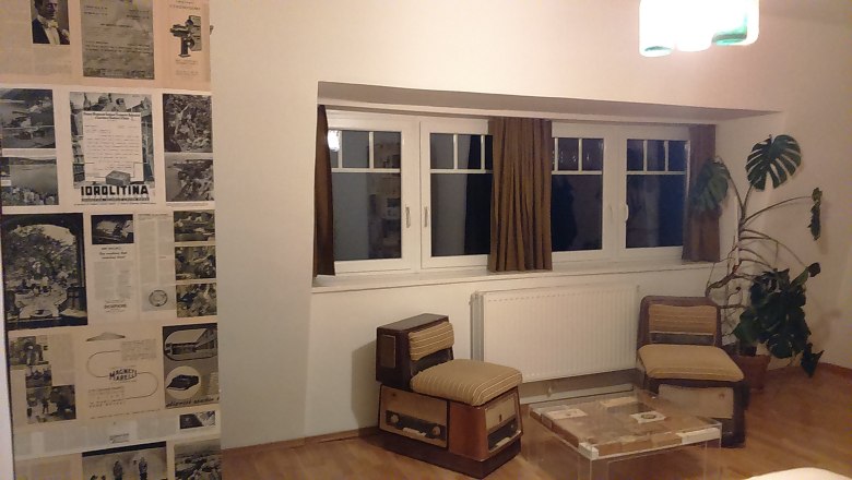 Hotelzimmer mit Retro-Möbeln, Zeitungswand und großer Pflanze.